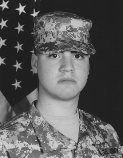A soldier in uniform with an american flag behind him.