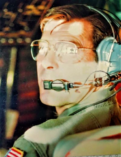 A man wearing headphones and glasses in an airplane.