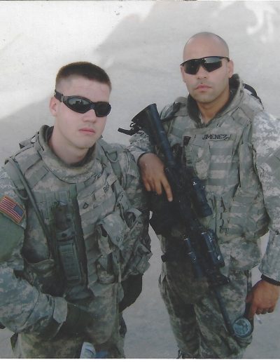 Two men in military uniforms holding a rifle.